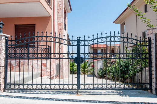 Picture of a wrought iron security gate next to a pink house